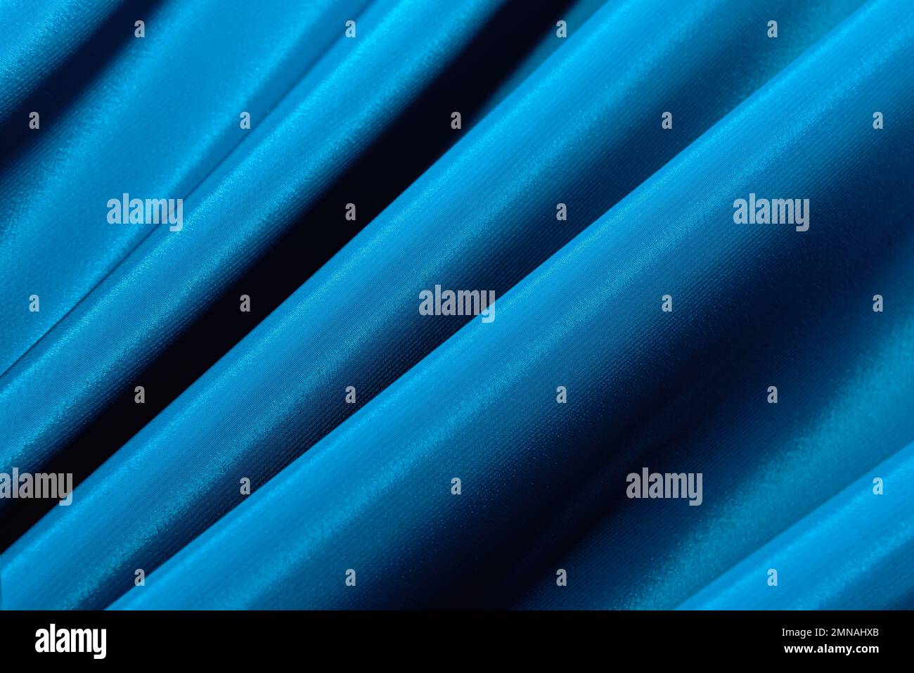 The texture of a smooth elegant fabric of silk, satin blue with folds
