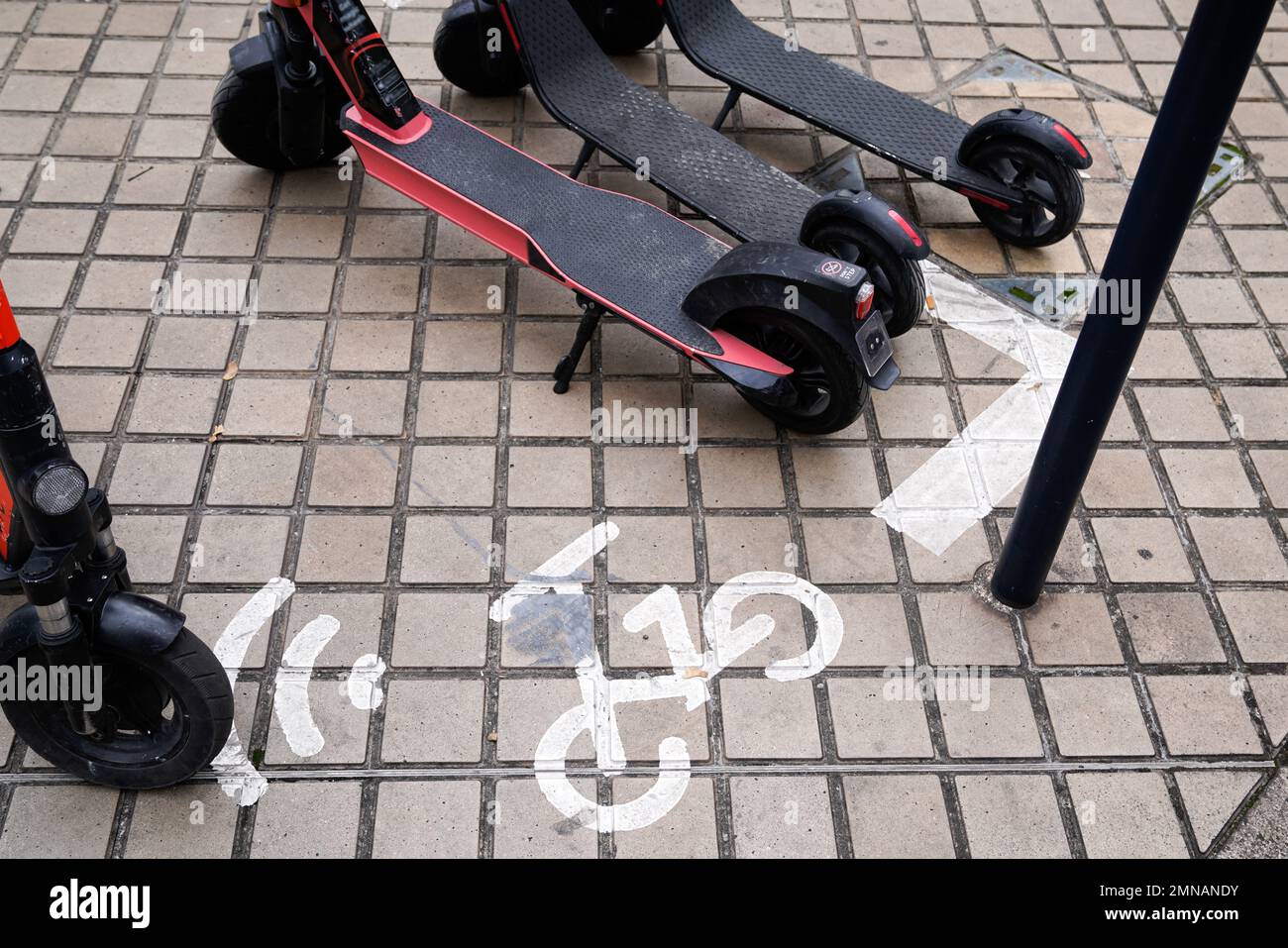 Scooters lined up on city sidewalk in downtown street pavement at old