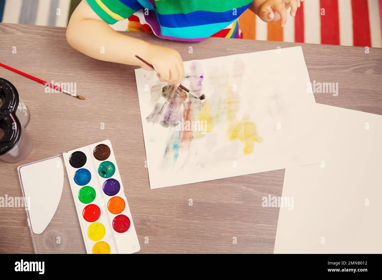 Little child drawing picture by using watercolors indoors. Stock Photo