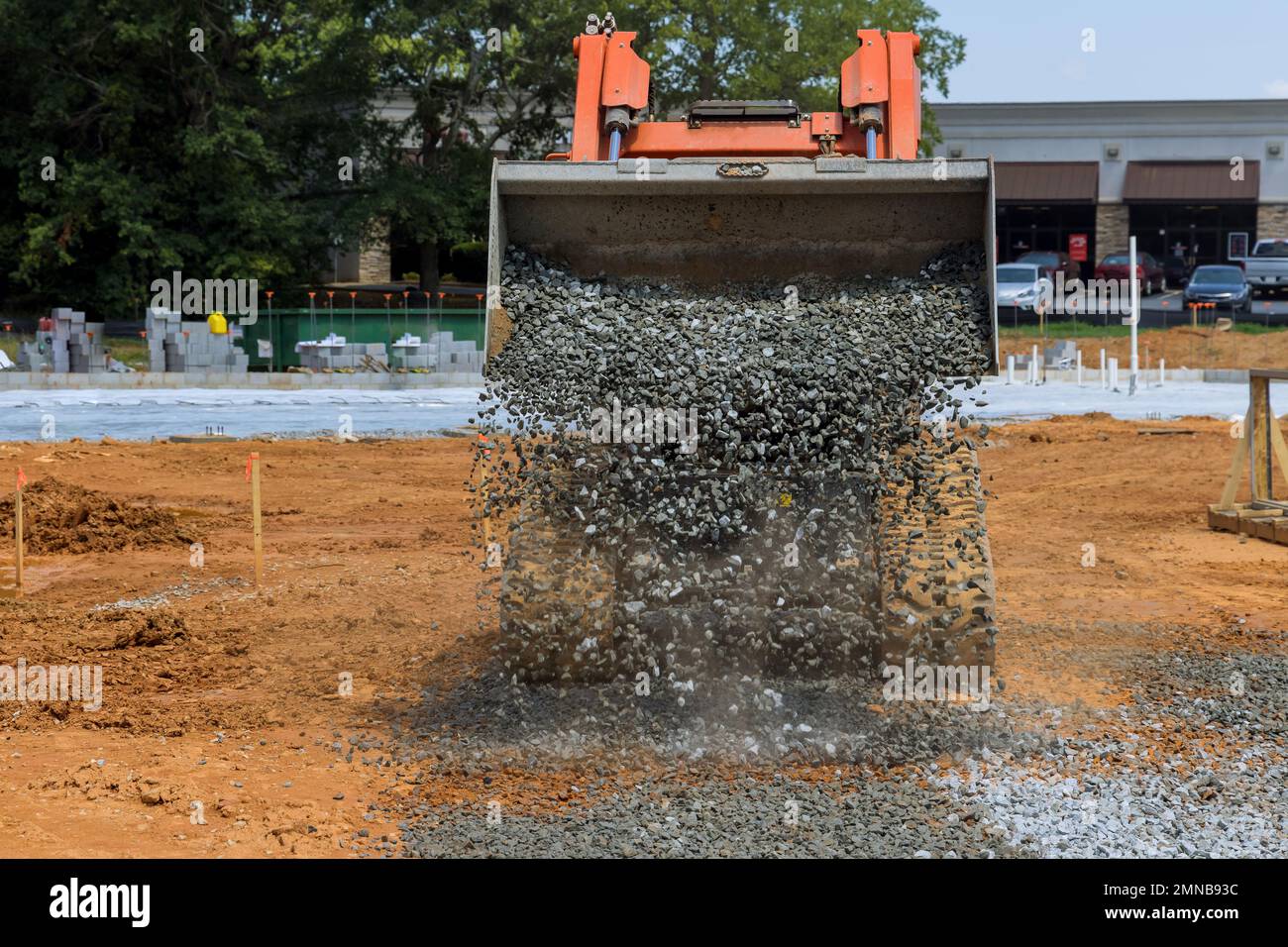 Bucket of crushed stone is being uploaded by an excavator into large scoop when bucket is full Stock Photo