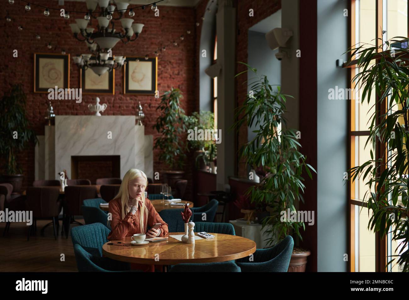Young restful albino woman scrolling in smartphone, watching online