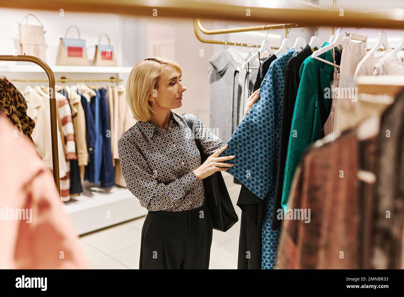 Elegant young woman choosing clothes in luxury boutique at shopping mall Stock Photo