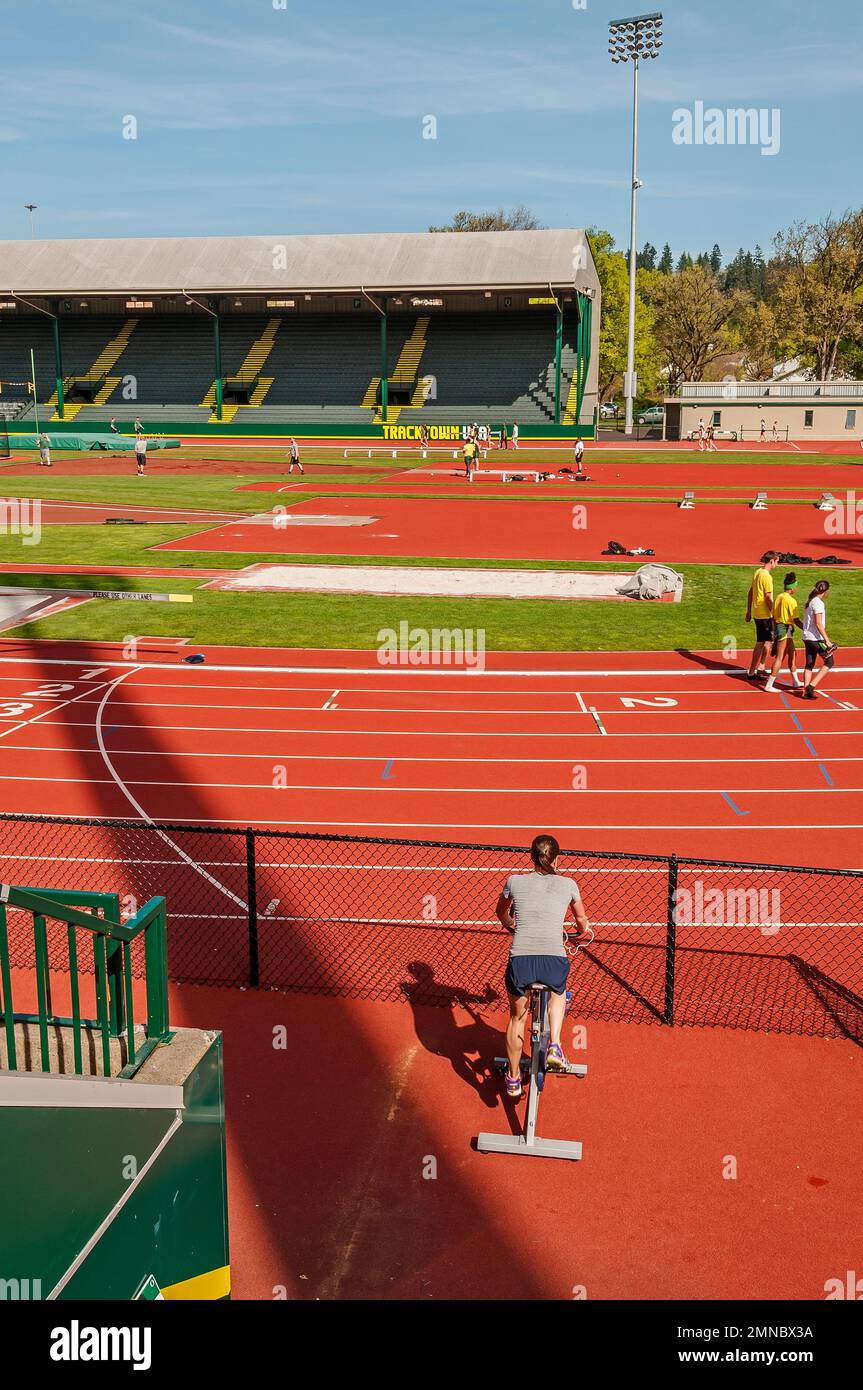 A woman rides a stationary bike outdoors at the University of Oregon