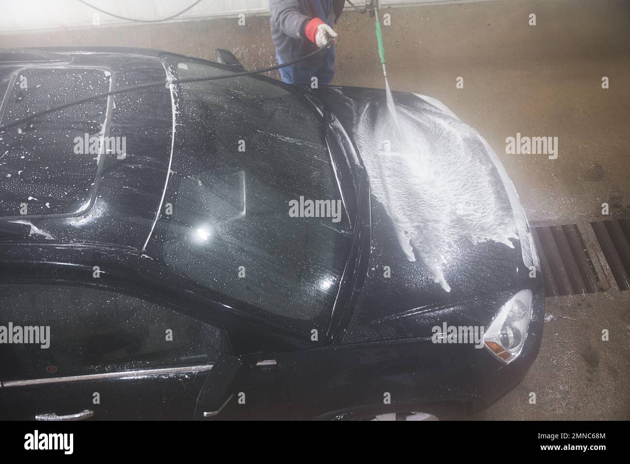 Black SUV getting washed with soap water in a car wash with a pressure