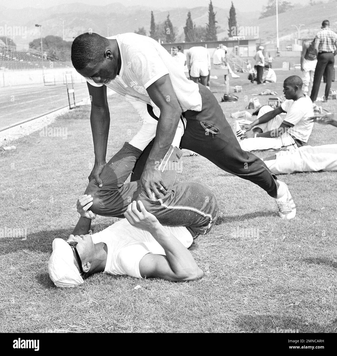 Sprinter Henry Carr gets his legs worked over by Bob Hayes at Mount San  Antonio College in Walnut, Calif., Sept. 8, 1964, where American track and  field stars are limbering up for