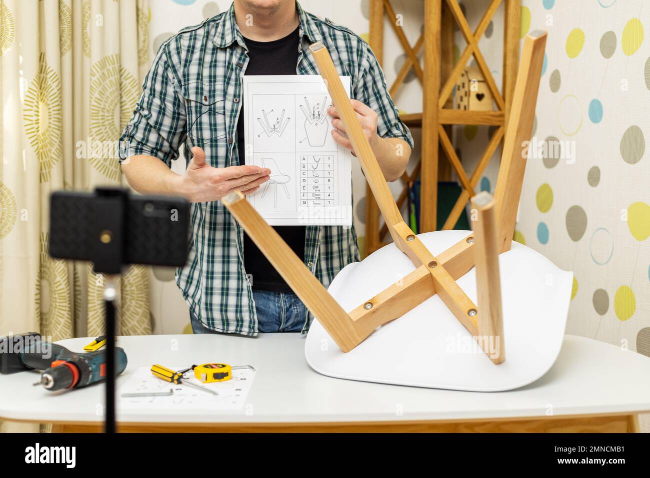 Handyman shows assembling chair, shooting video instructions on