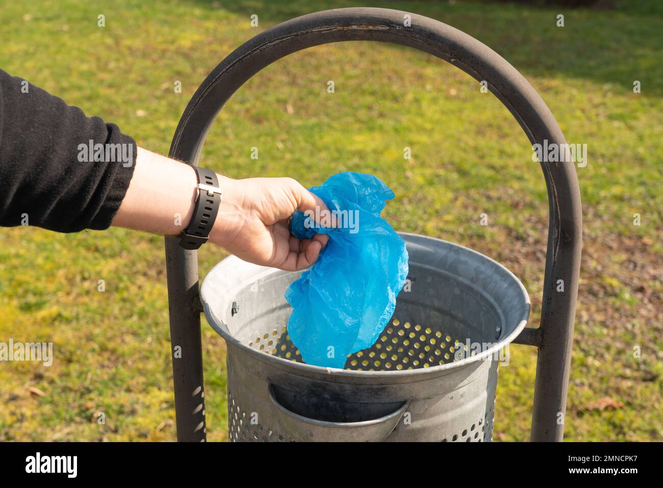 Closeup of man throwing away trash in garbage container while taking a