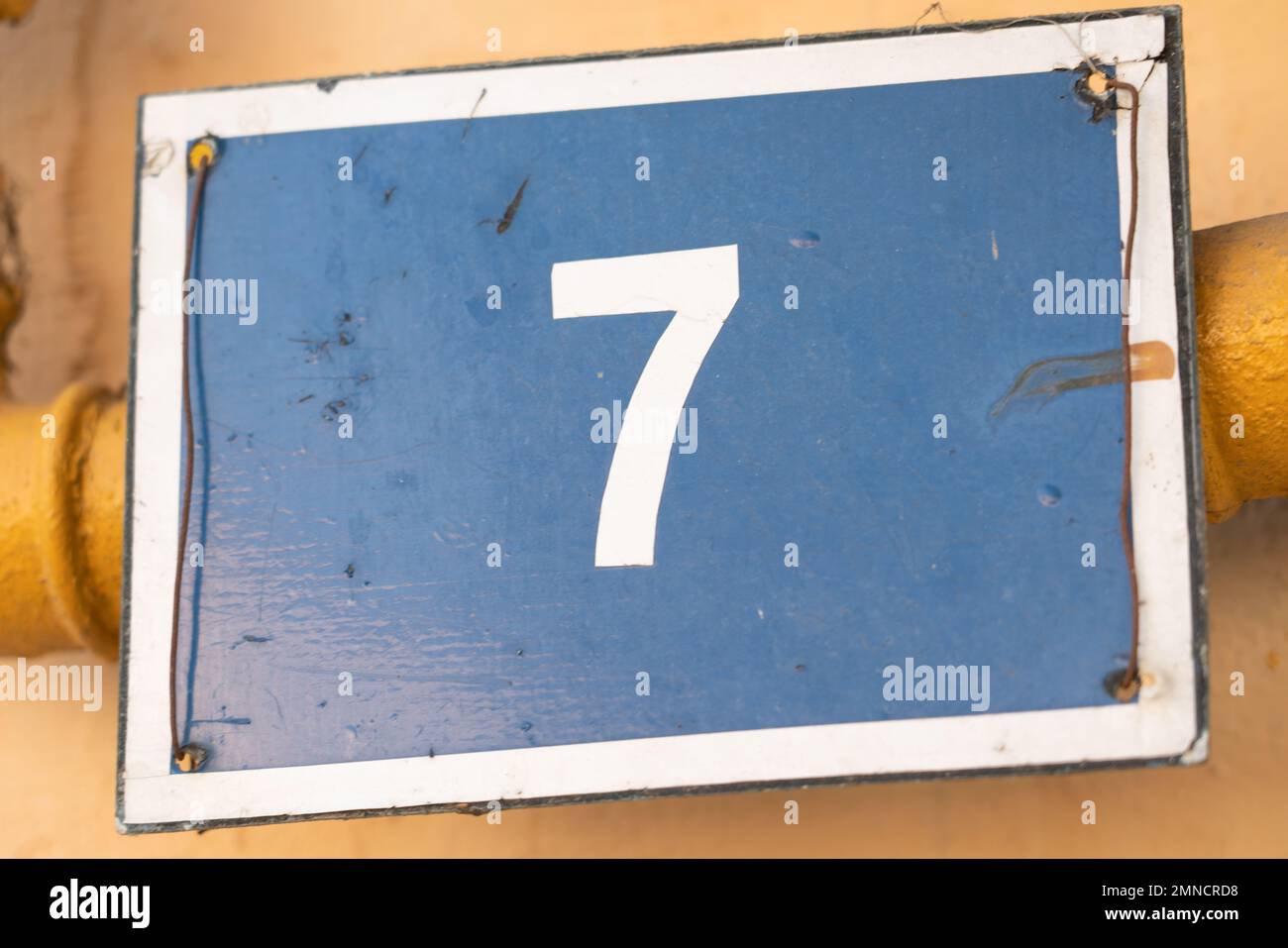 Closeup of blue placard of seven house number as family residence