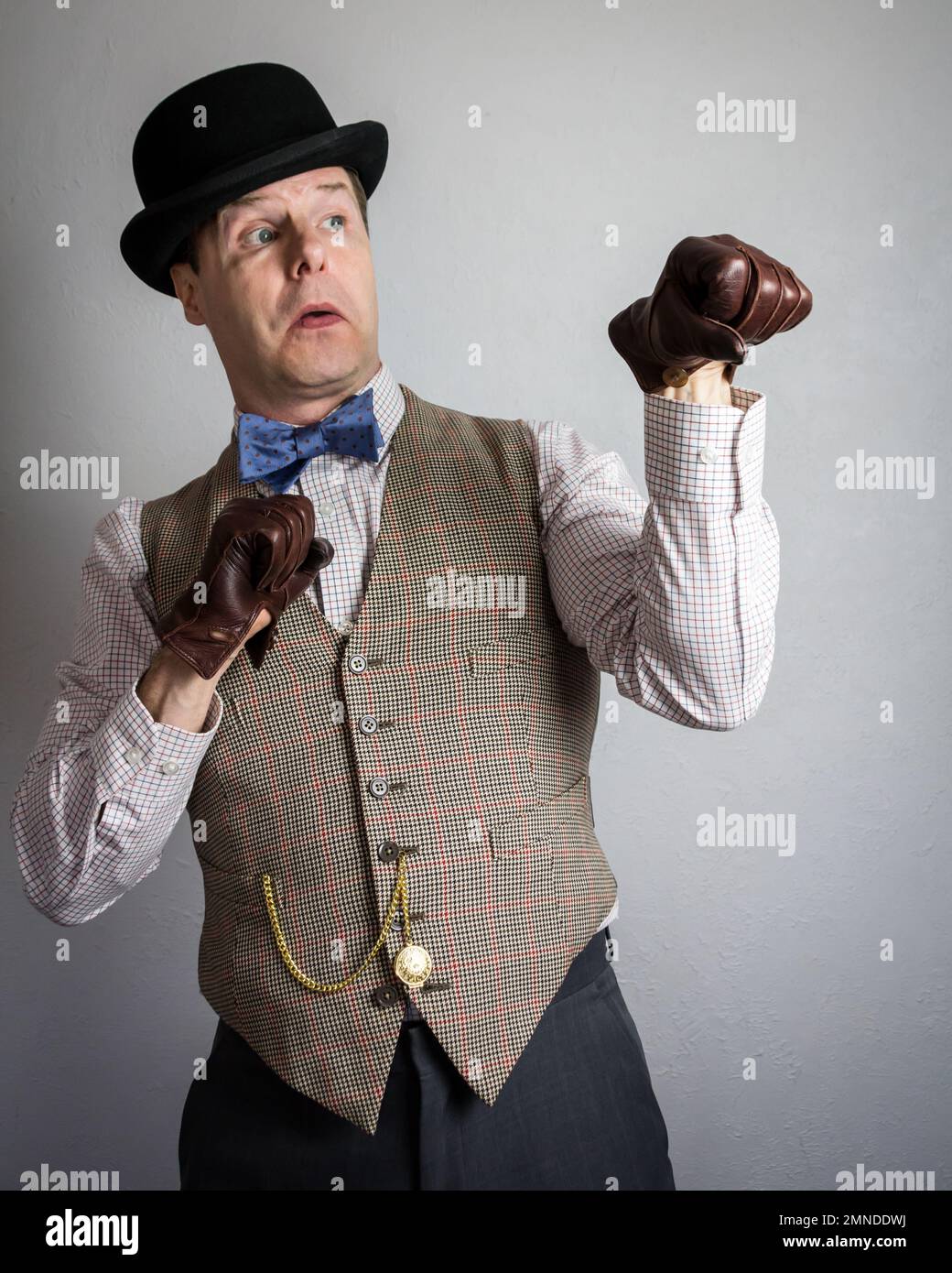 Man in Tweed Vest and Bowler Hat and Leather Gloves Standing in Fearful Fighting Pose. Concept of Vintage British Ruffian or Thug Stock Photo