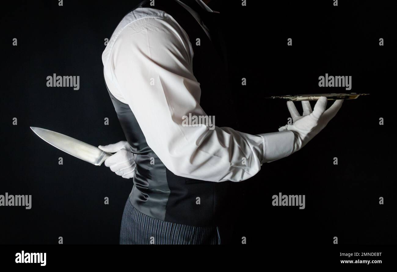 Butler or Waiter With Serving Tray and Holding Sharp Knife Behind Back. Concept of Butler Did It. Classic Murder Mystery. Stock Photo