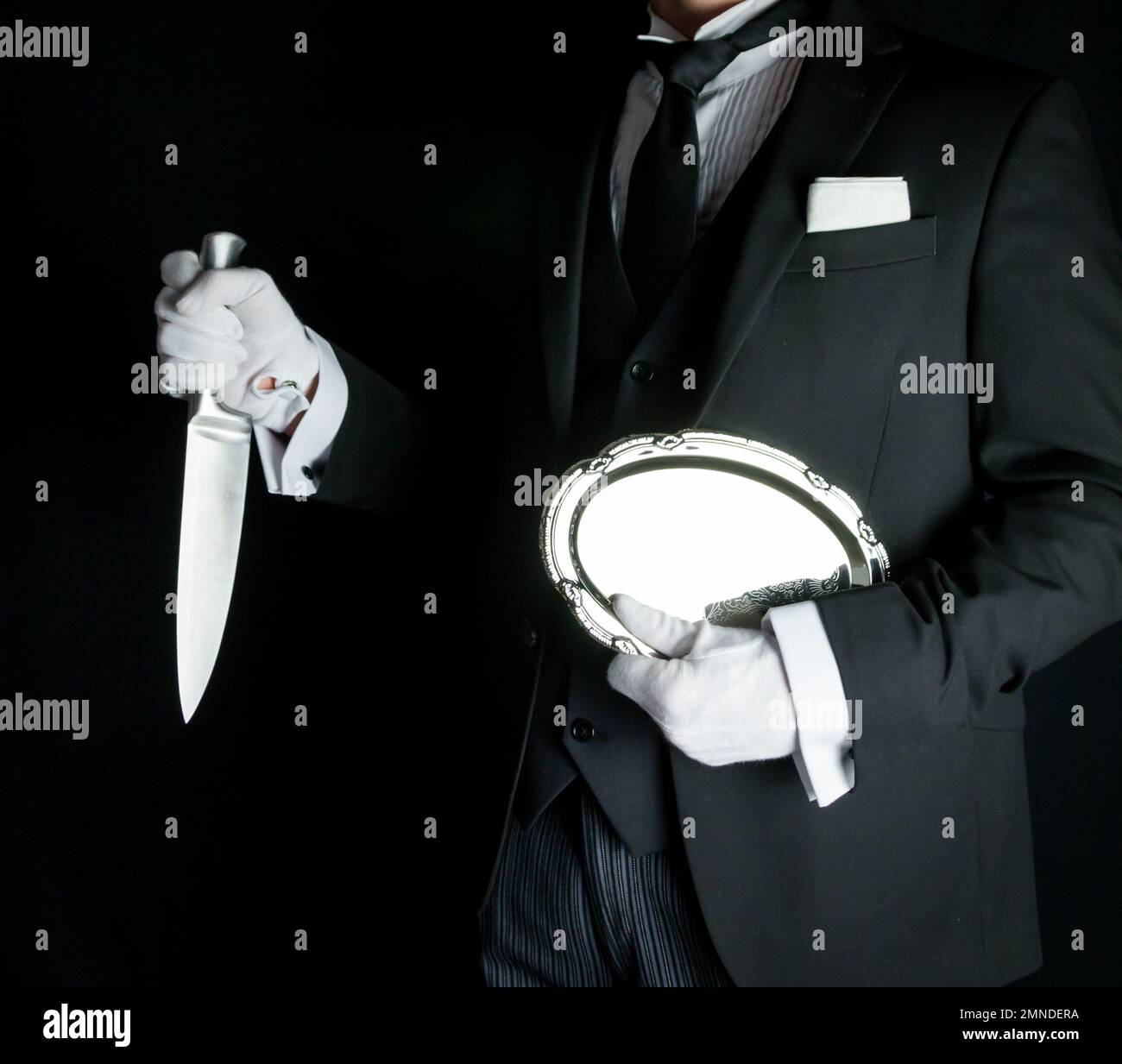 Butler in Dark Suit Holding Silver Serving Tray and a Sharp Knife. Concept of Butler Did It Classic Murder Mystery Stock Photo