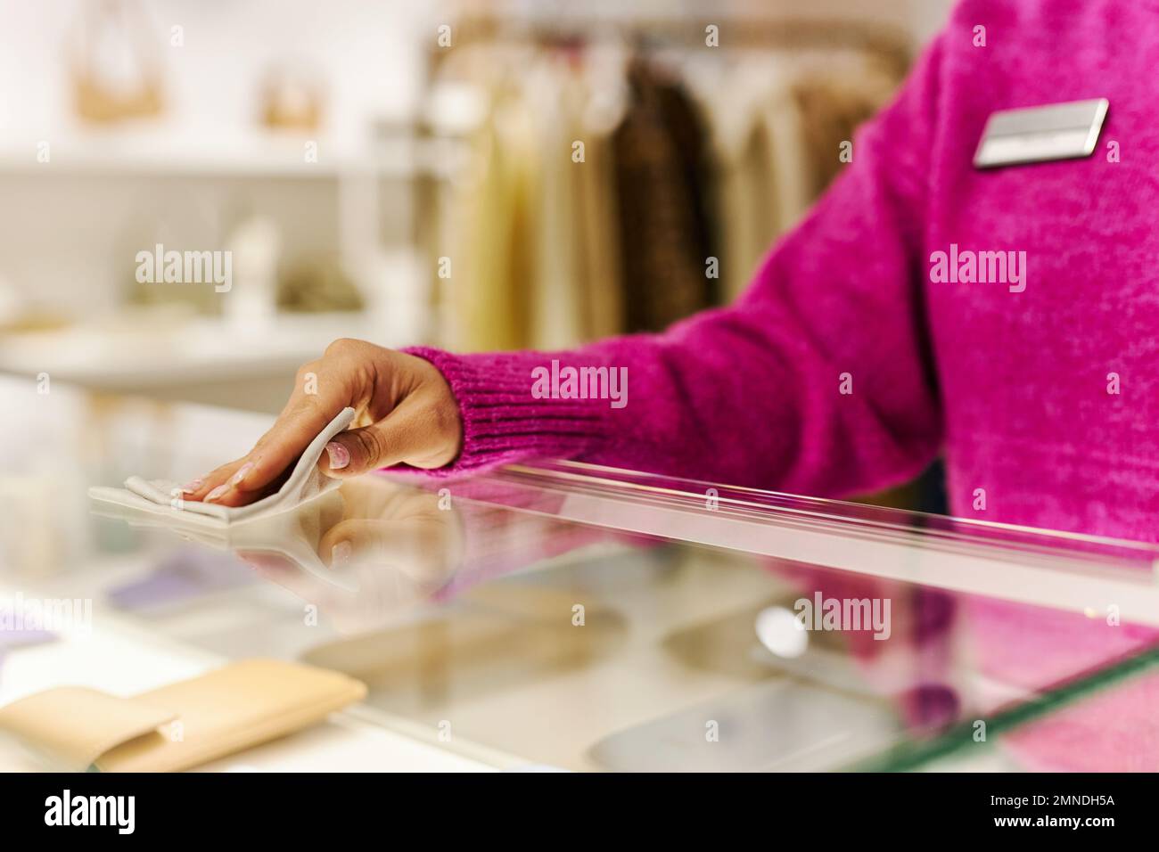 Close up of sales manager wiping glass counter in luxury boutique while preparing shop for opening, copy space Stock Photo