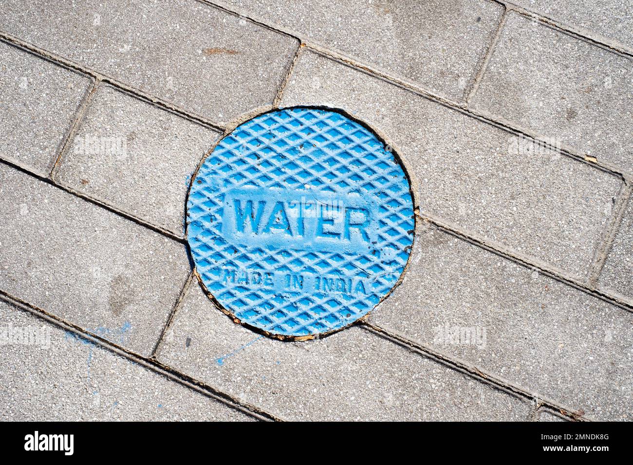 A round cover with the word 'WATER' in the sidewalk. Stock Photo