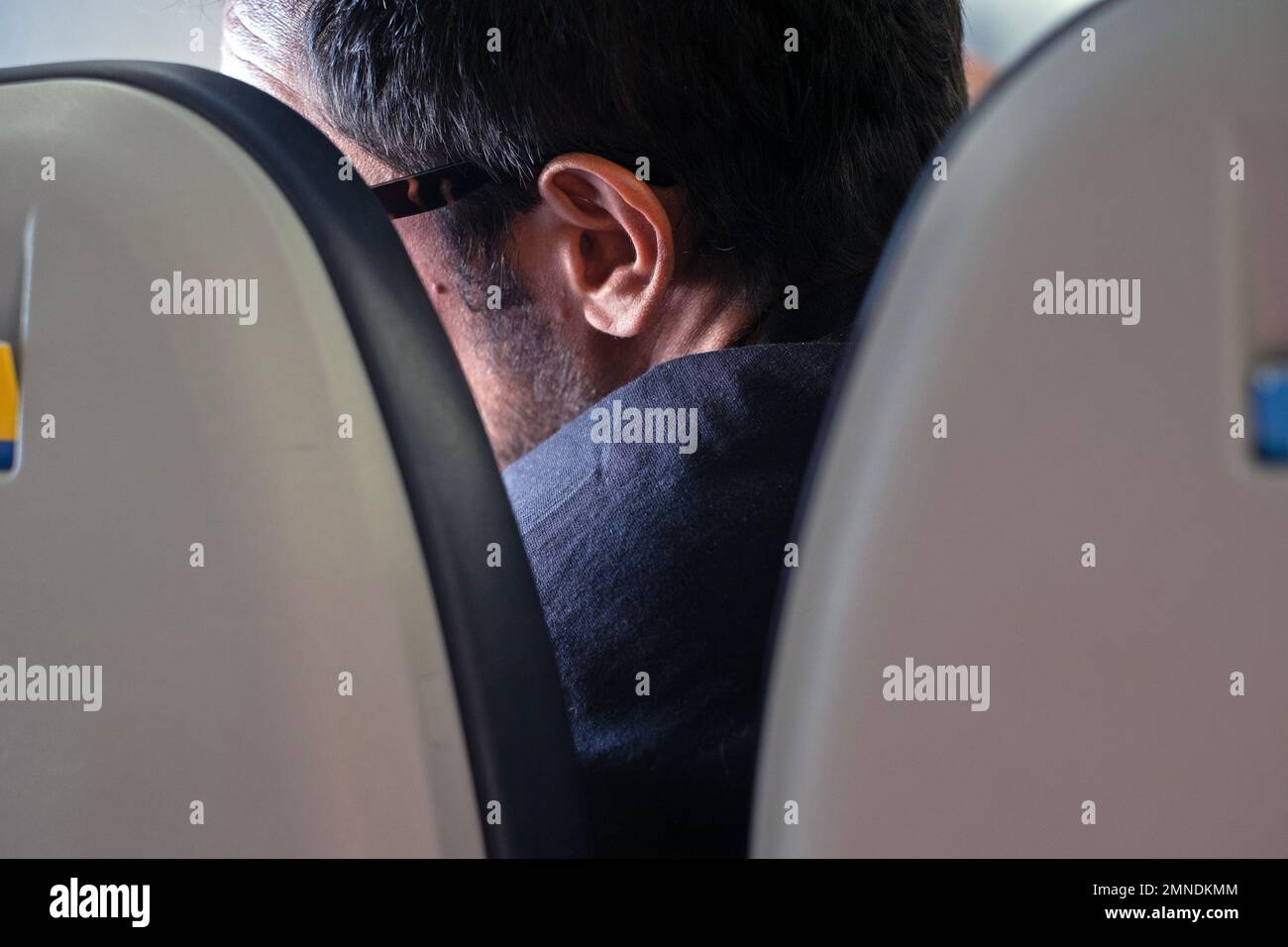A man looks out a window of an airplane during flight. Stock Photo