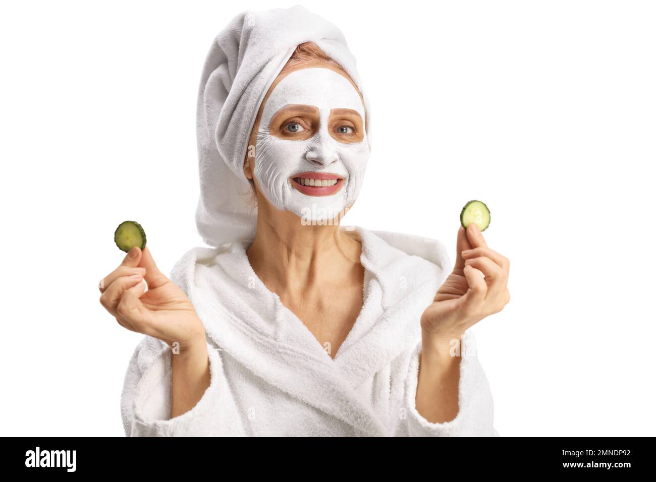 Beautiful woman with towel on her head and a face mask holding pieces of cucumber isolated on white background Stock Photo