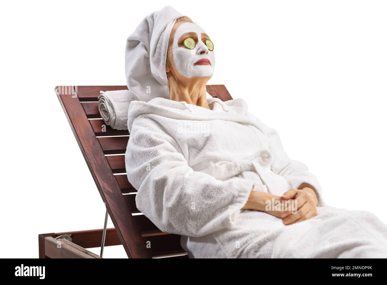Woman with towel on her head and a face mask resting on a lounge chair isolated on white background Stock Photo
