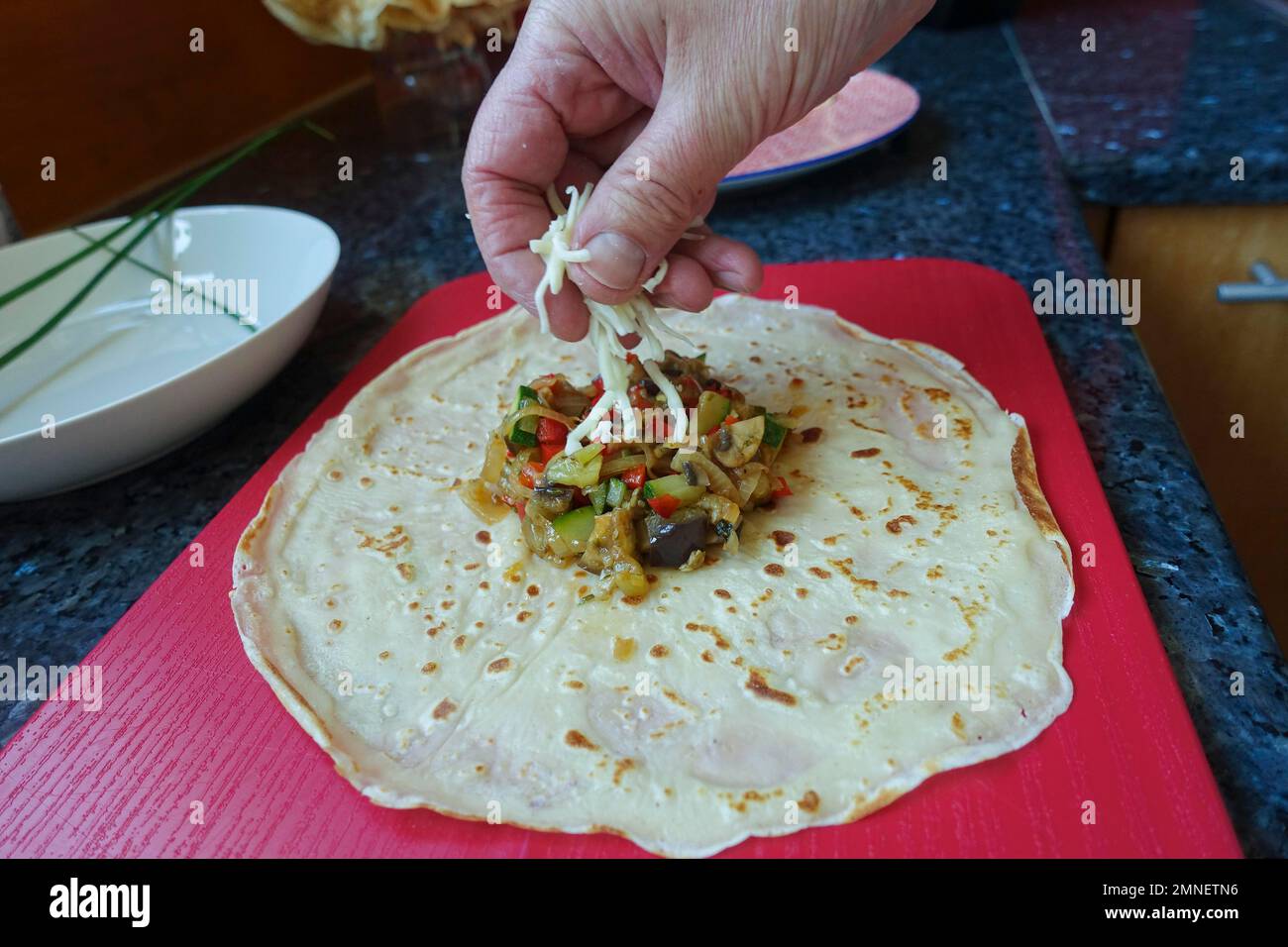 Swabian cuisine vegetarian, preparation surprise Flaedle, filled Flaedle, pancake hearty fill with vegetables and sprinkle with cheese, man hand Stock Photo
