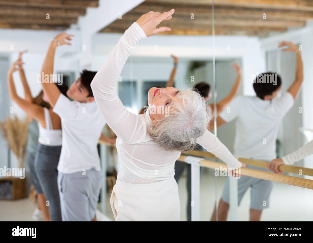 Elderly woman doing choreography at ballet barre Stock Photo