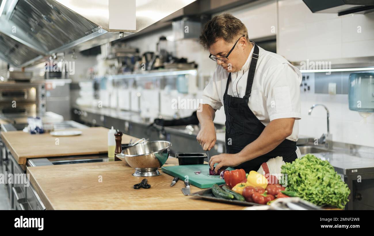 male chef with apron chopping vegetables. Resolution and high quality ...