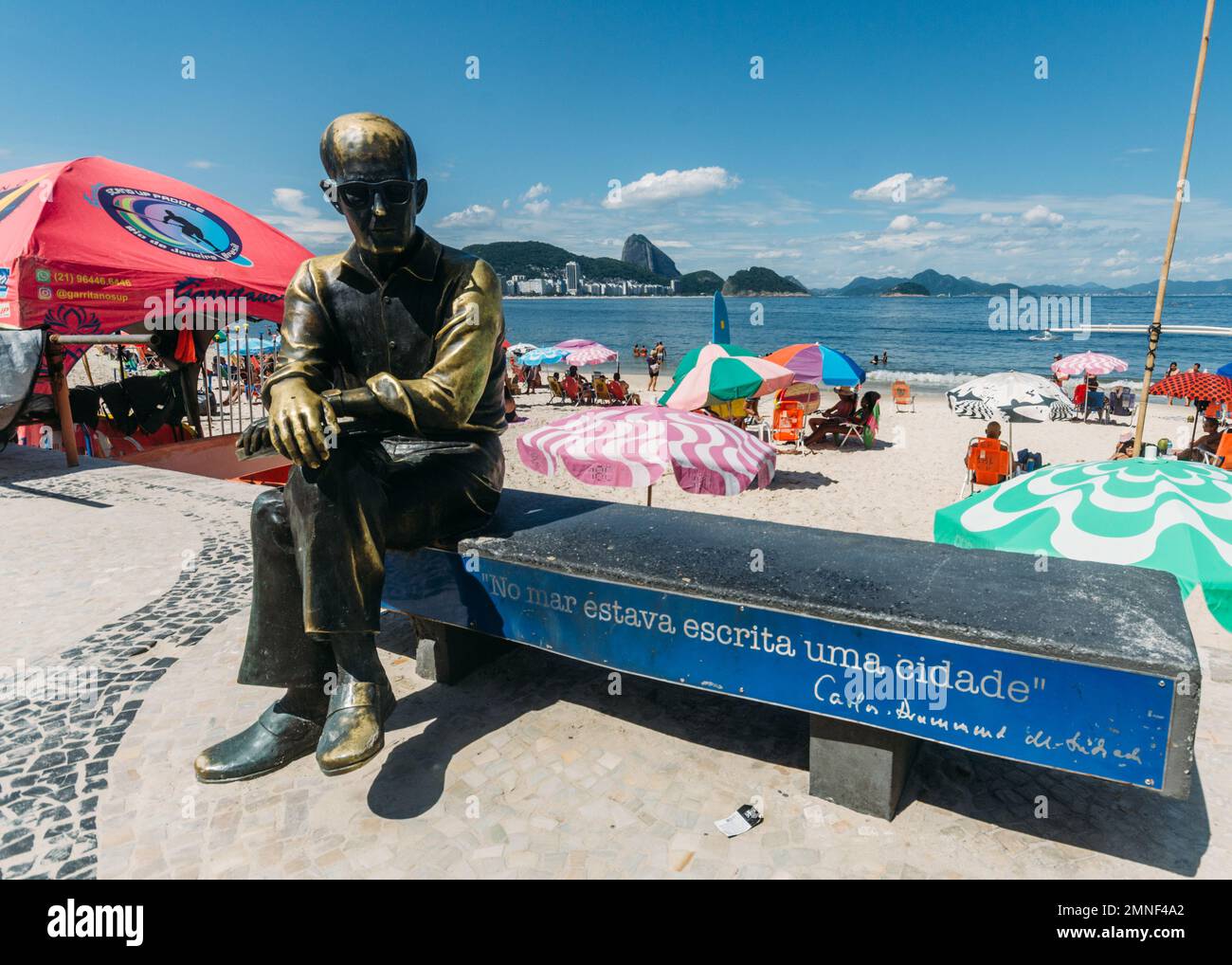 Rio de Janeiro, Brazil - January 30, 2023: Copacabana sidewalk, sightseeing spot statue of poet Carlos Drummond de Andrade sitting on bench at beach Stock Photo