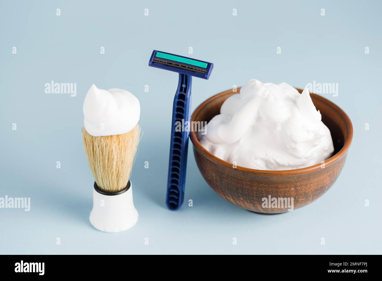 razor shaving brush bowl foam against blue backdrop. High resolution