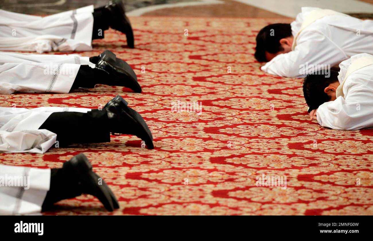 New priests lie face down on the floor during an ordination ceremony presided over by Pope