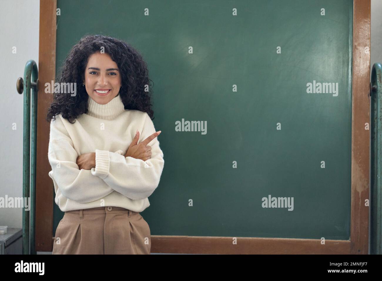 Young happy business woman teacher pointing at empty blackboard. Stock Photo
