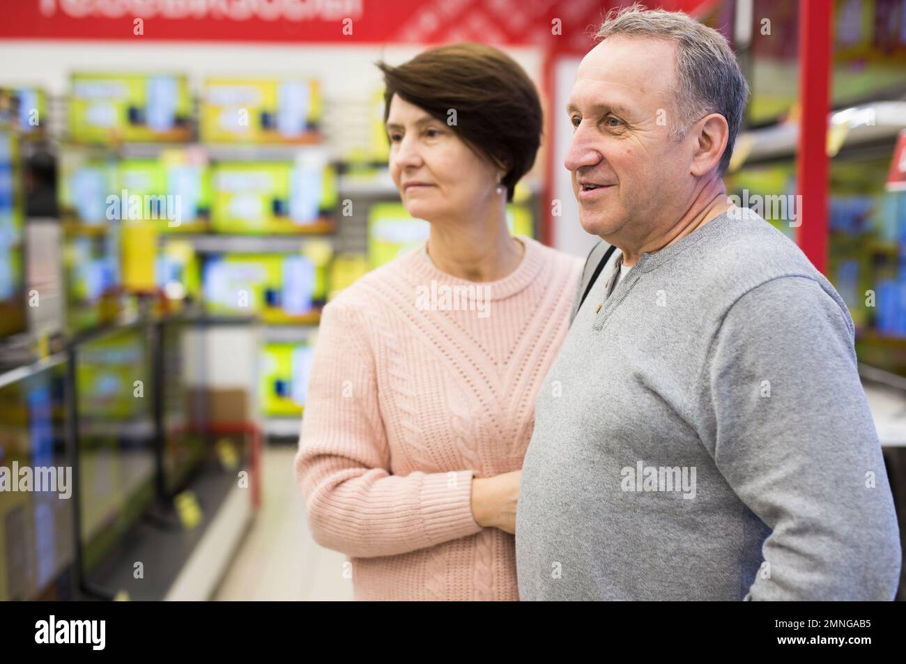 Senior couple picking new TV in tech store Stock Photo
