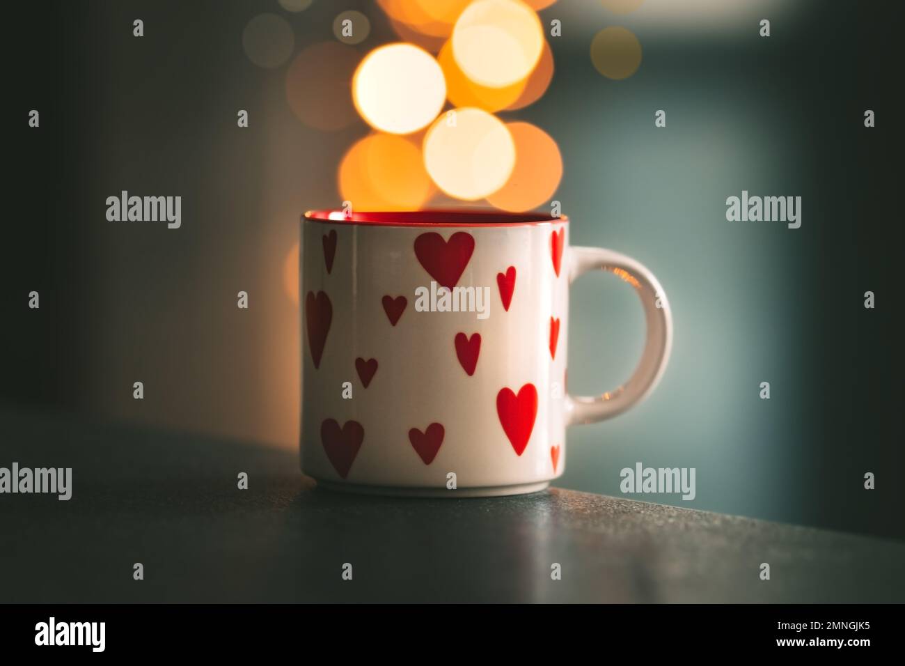 A cup of tea with or coffee with hearts on it is standing on table with bokeh on background. Saint Valentines day or love concept.  Stock Photo
