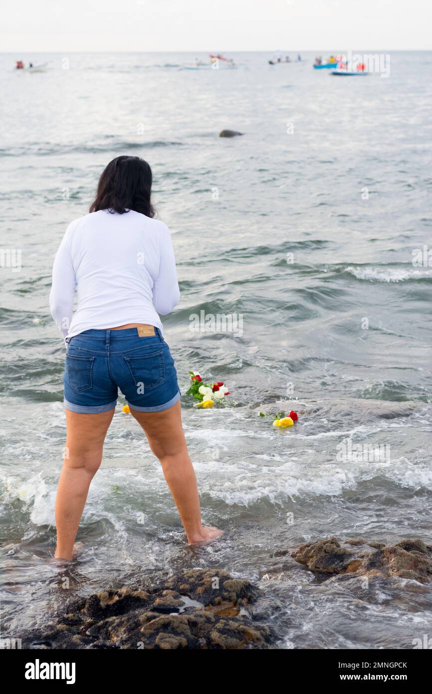 Salvador, Bahia, Brazil - February 02, 2017: Candomble admirers are seen on top of a rock on the beach, paying homage to Iemanja with gifts on the day Stock Photo
