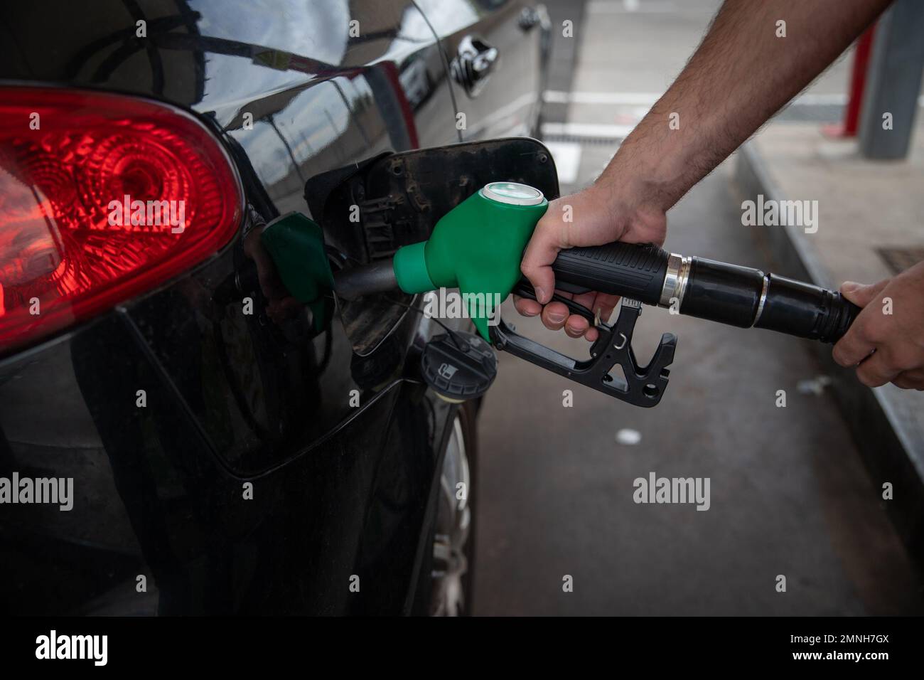A man refuels his car, close-up on the hand holding the gas nozzle Stock Photo