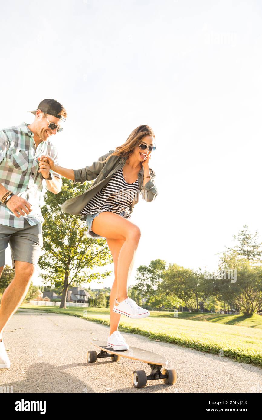 Smiling couple with skateboard in park Stock Photo