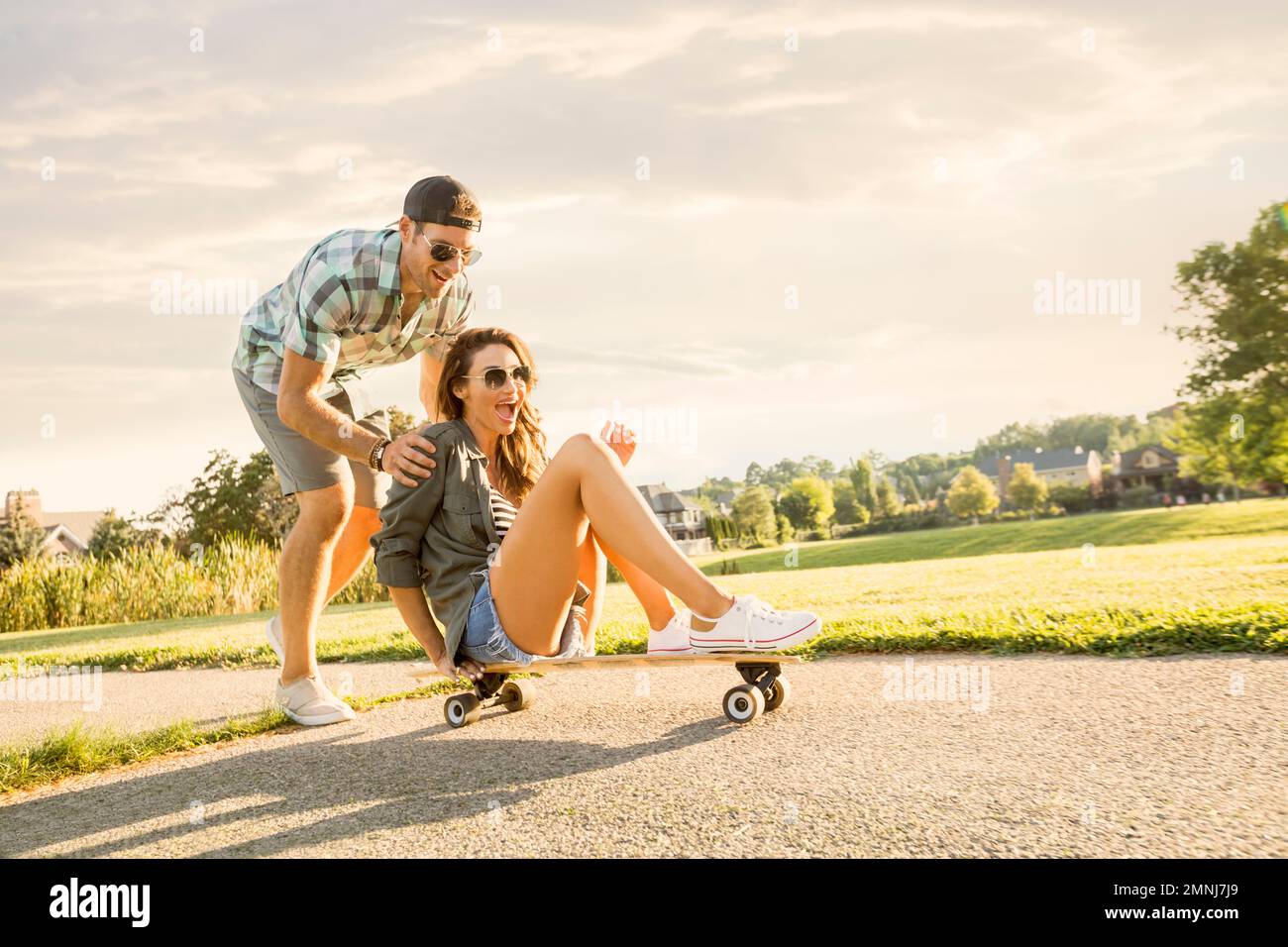 Smiling couple with skateboard in park Stock Photo