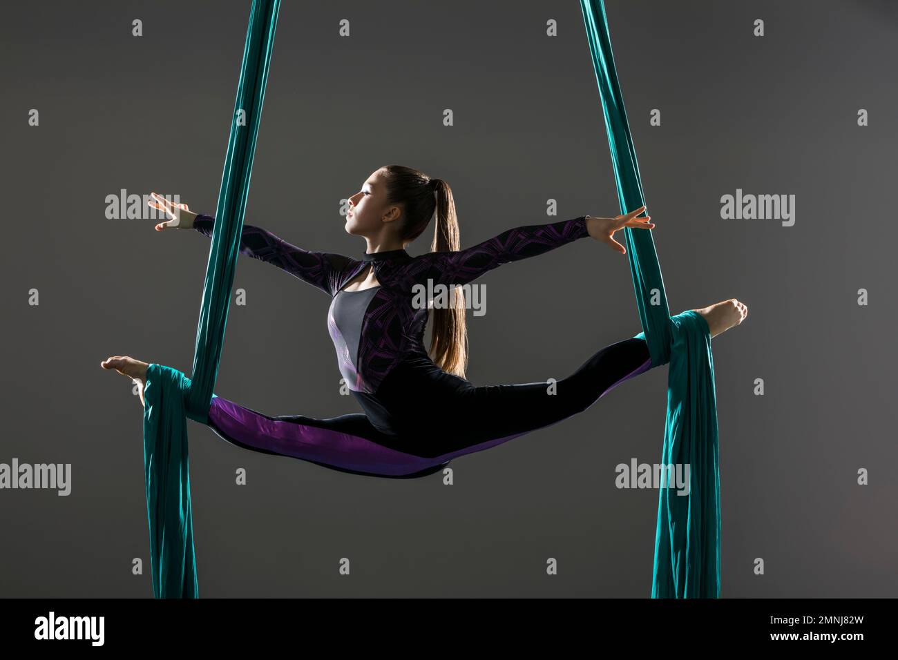 Young acrobat doing splits on aerial silks Stock Photo