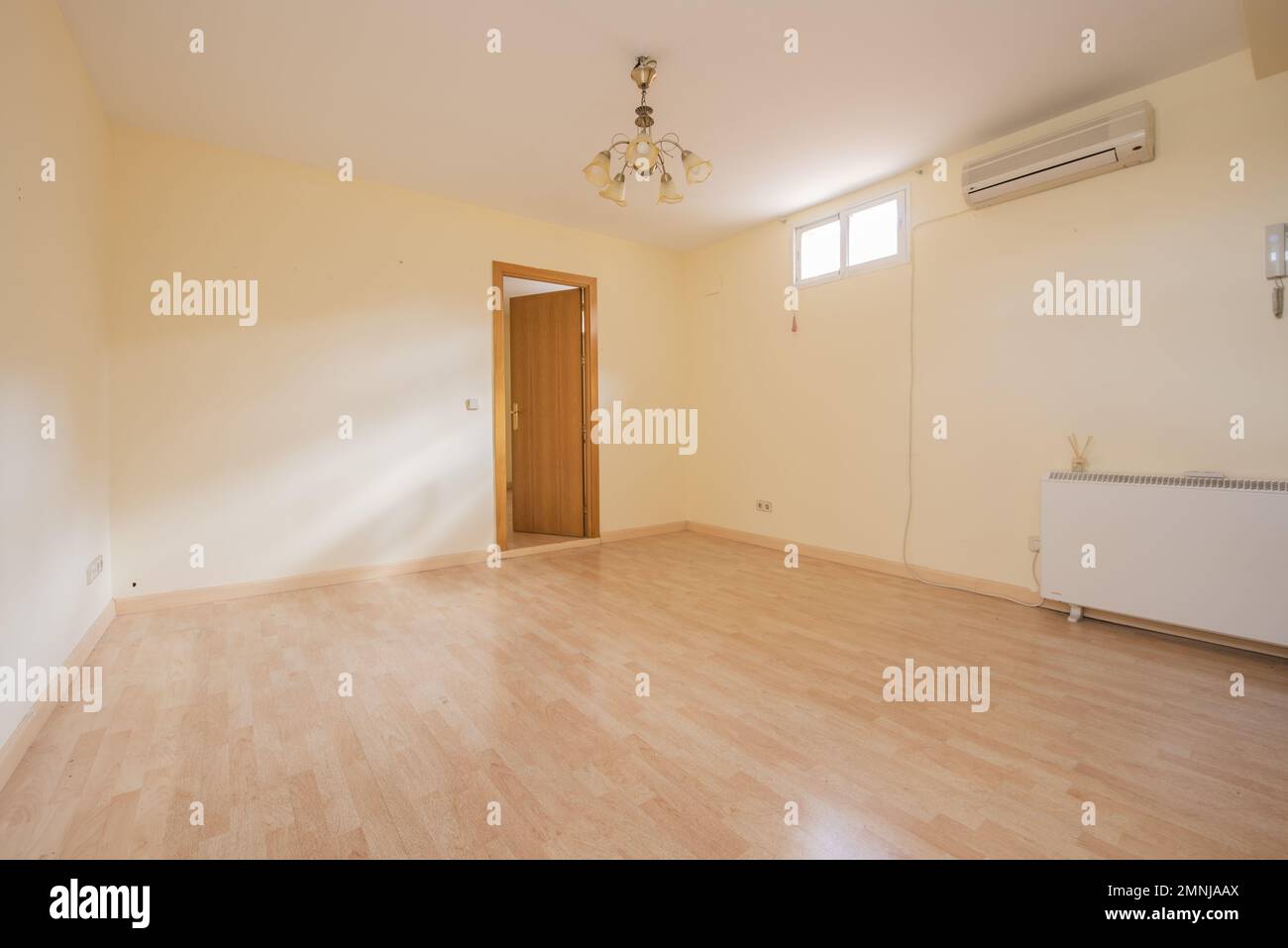 Empty living room with light yellow walls, light wooden floor, electric
