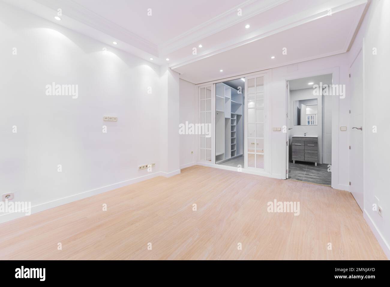 Empty bedroom with sliding doors to a dressing room and en-suite bathroom Stock Photo