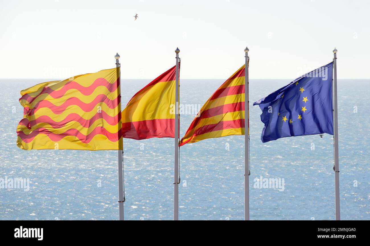 flags of tarragona, spain, catalonia and european union with a sea of