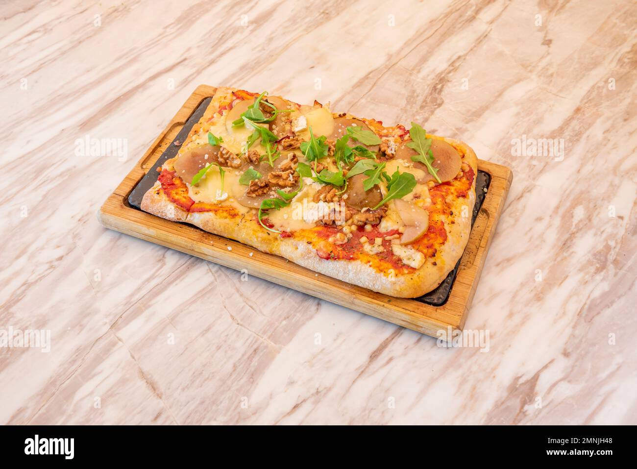 Small rectangular pizza with pear slices, california walnuts, brie cheese and arugula leaves Stock Photo