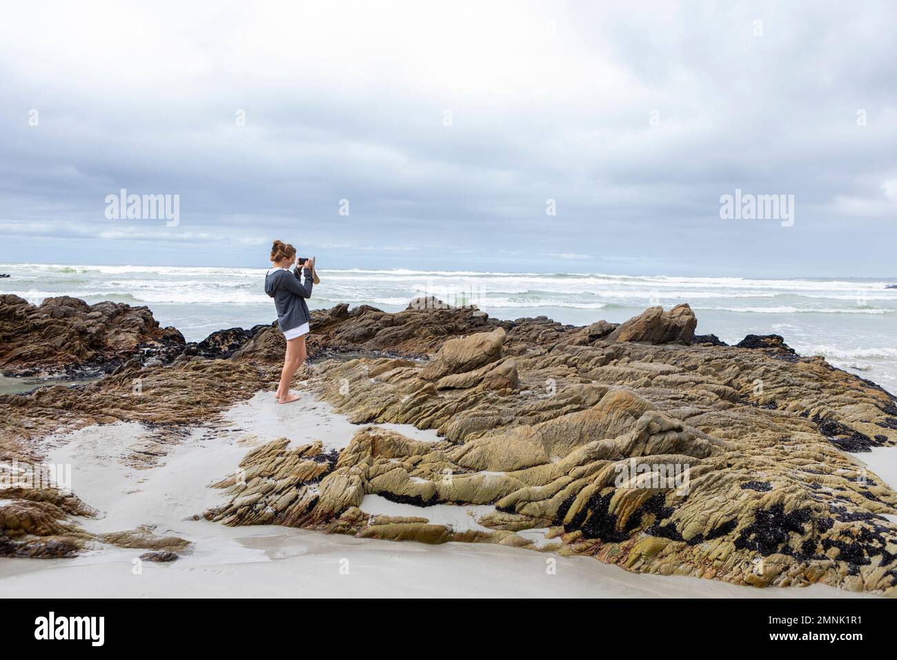 South Africa, Hermanus, Teenage girl (16-17) taking photos on Voelklip beach Stock Photo