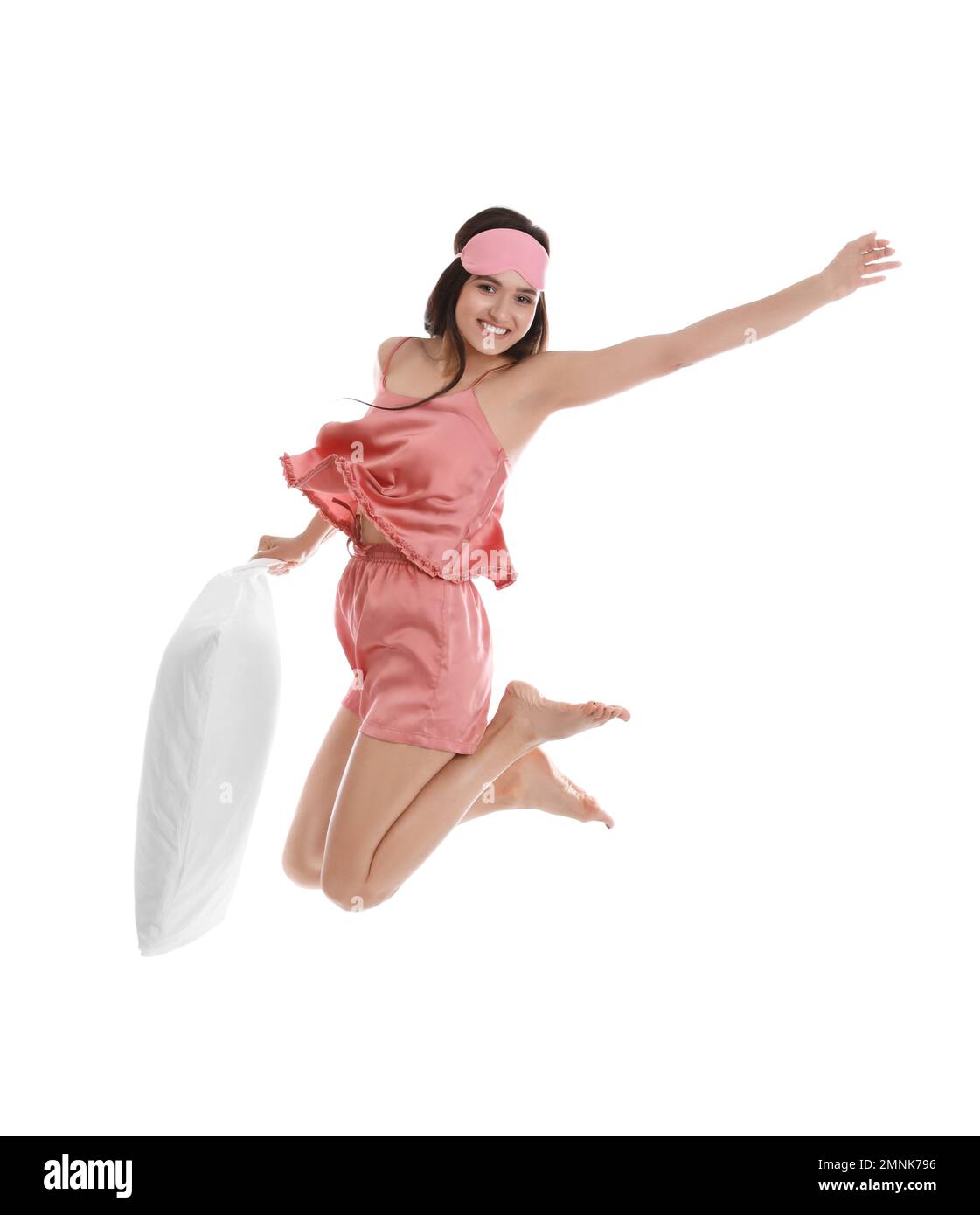 Beautiful woman with pillow jumping on white background. Bedtime Stock