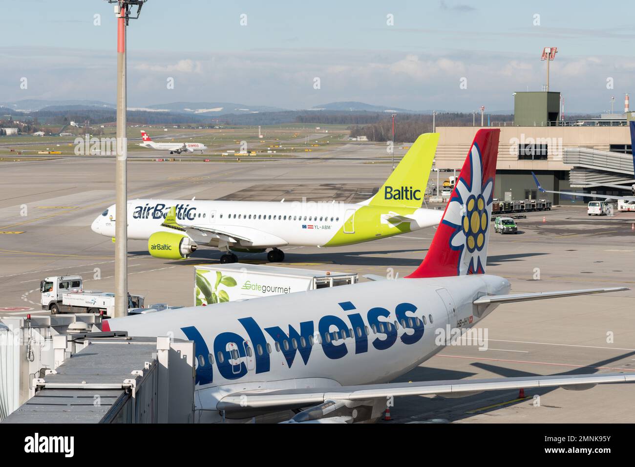 Zurich, Switzerland, January 19, 2023 Air Baltic Bombardier CS-300 and an Edelweiss Airbus A320-214 aircraft at the gate Stock Photo
