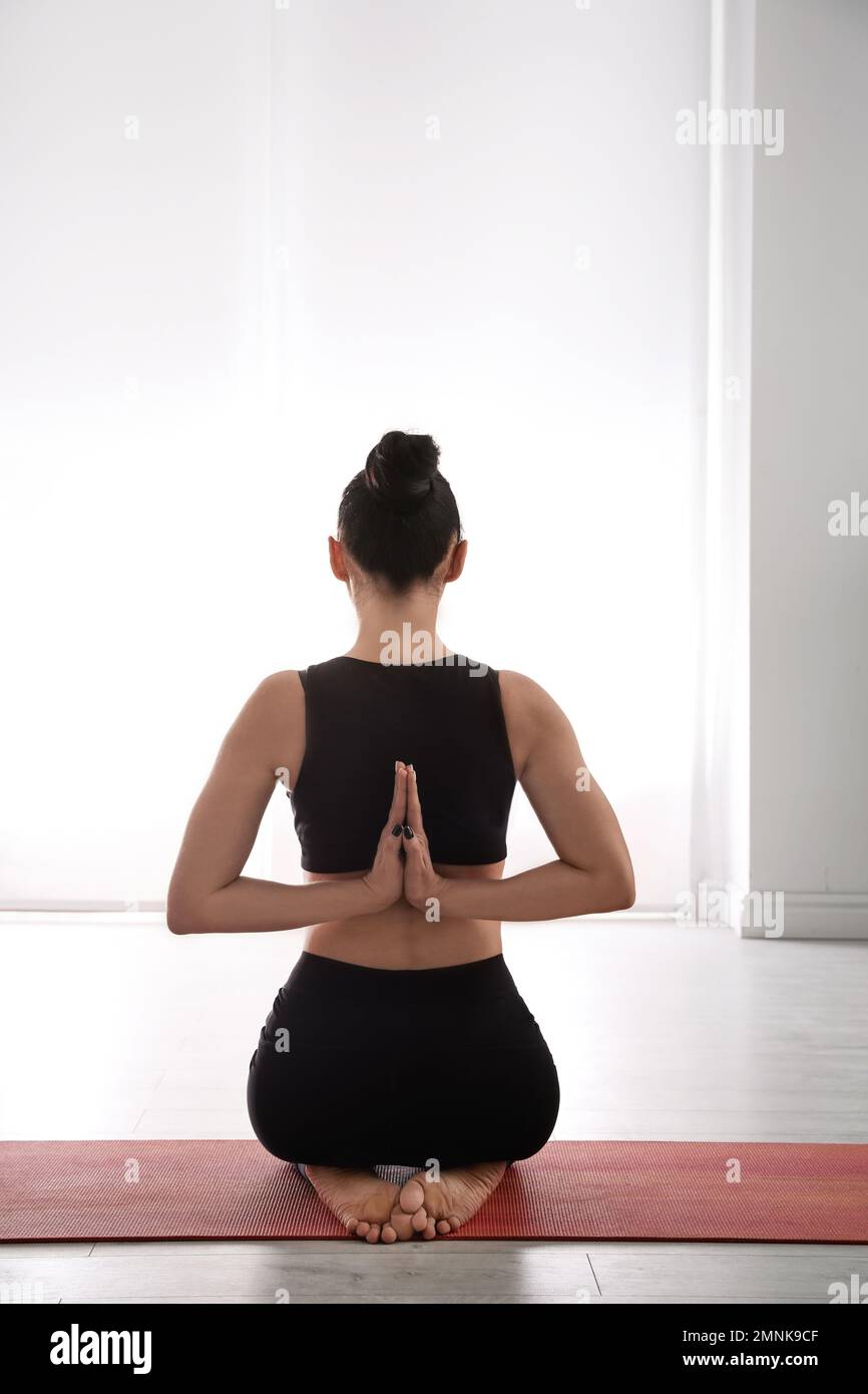 Woman in Hatha yoga asana Vajrasana, vajra pose or diamond pose on yoga mat  on yoga mat in studio on grey bagckground. - Album alb8402947