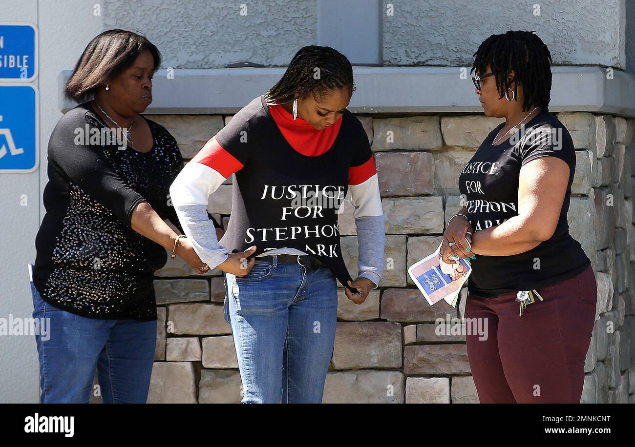 A woman gets help putting on a T-shirt calling for Justice For Stephon Clark,  before entering of the Bayside of South Sacramento Church, known as BOSS  Church, for Clarks' wake Wednesday, March