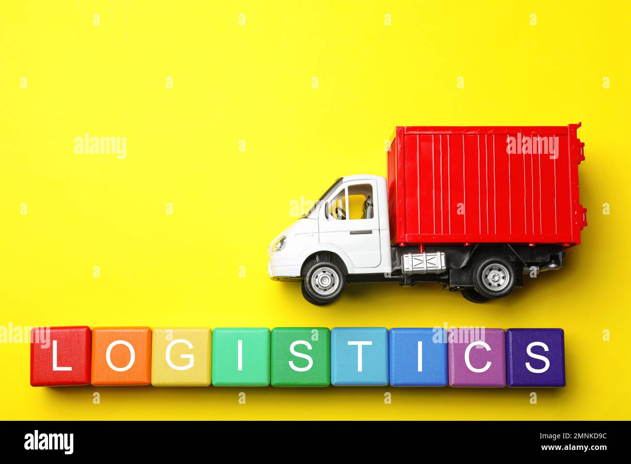 Flat lay composition with toy truck and word LOGISTICS on yellow background, space for text. Wholesale concept Stock Photo