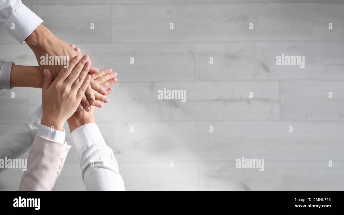 People holding hands together over light wooden background, top view ...