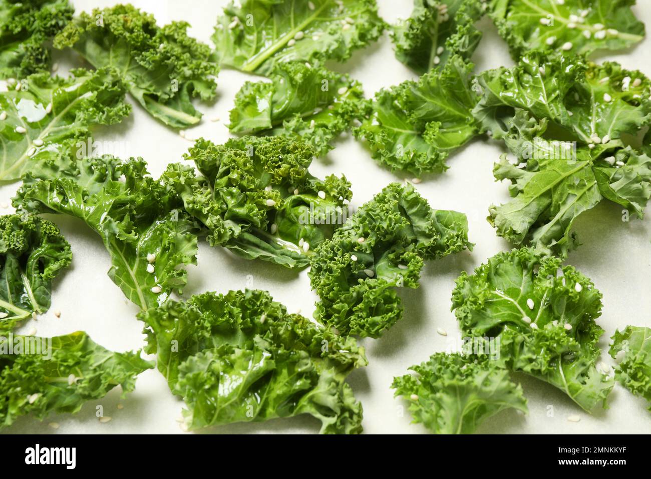 Raw cabbage leaves on parchment paper, closeup. Preparing kale chips