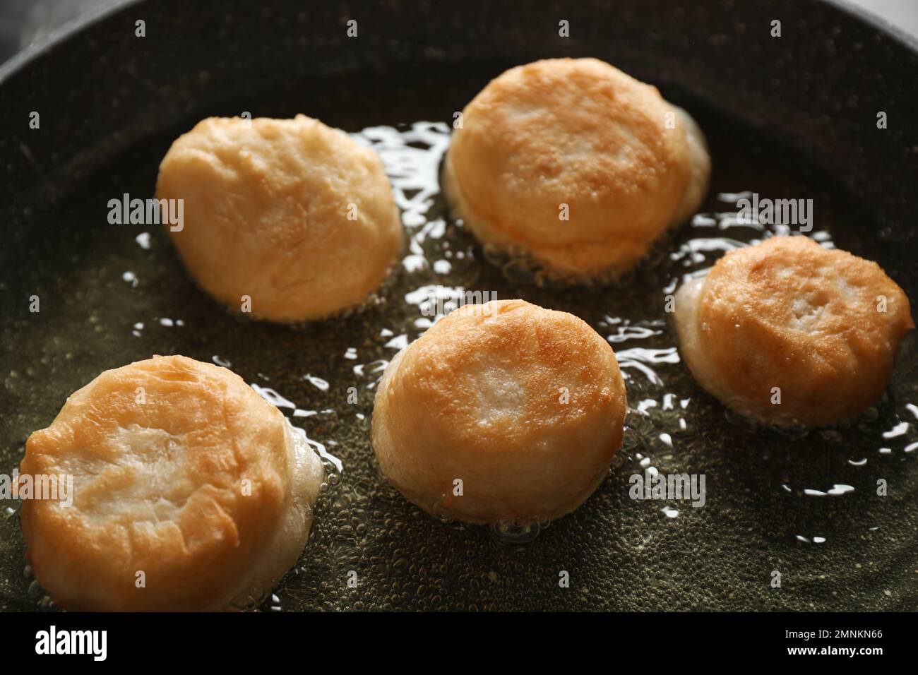 Cooking delicious donuts in hot oil, closeup Stock Photo Alamy