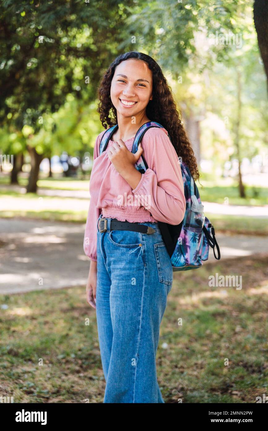 Smiling young latin student woman standing in the park. Determination. Centennial generation Stock Photo