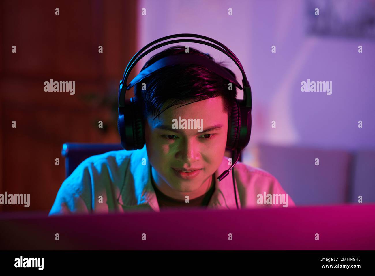 Smiling teenage boy wearing headset when playing videogame at home