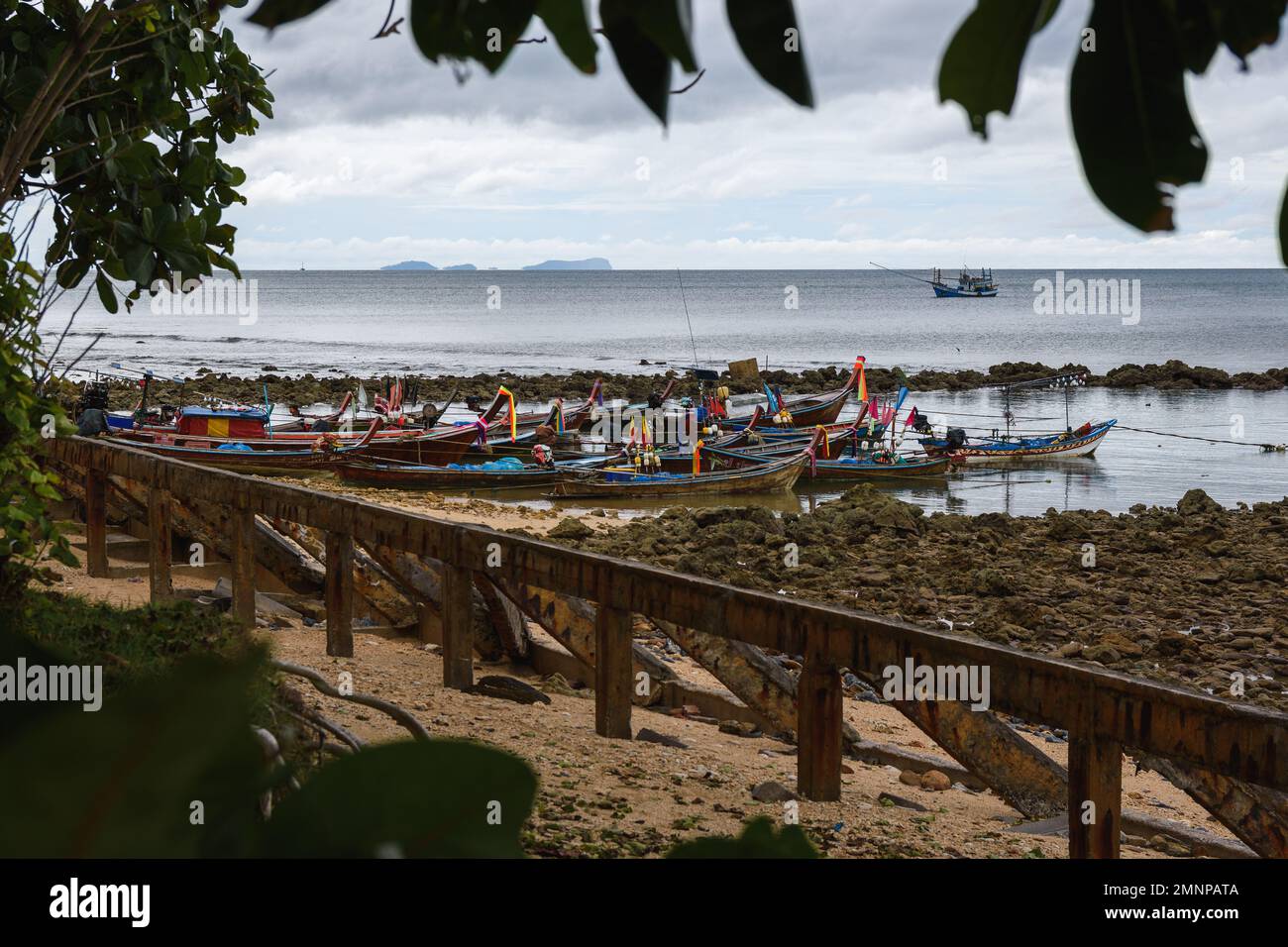 Group of long tail boats next to a rocky beach in Ko Lanta, Krabi, Thailand. December 4, 2022